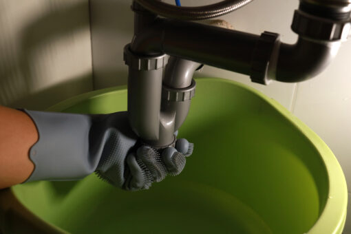Man fixing a pipe under his kitchen sink close up